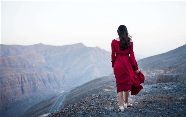 دختر شیک پوش در بالای کوه بیابانی با لباس قرمز