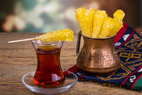 از نزدیک از آب نبات سنگ زعفران کریستال قند روی فنجان چای سیاه اغلب برای حل شدن در چای در غذاهای ایرانی ایرانی استفاده می شود