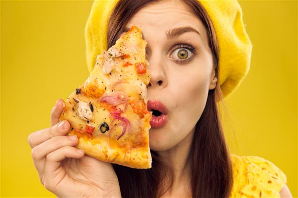 زن متعجب با کلاه بری با پیتزا در زمینه زرد