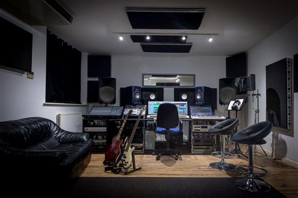 اتاق کنترل استودیو ضبط کامل با میز میکس کامپیوتر و تجهیزات بیرونی همچنین در تصویر گیتار کیبورد میکروفون و سینت سایزرها دیده می شود