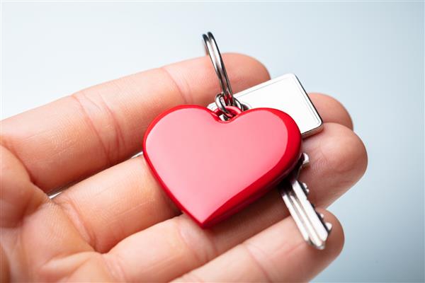نمای نزدیک از دست شخصی که در دست یک زنجیر کلید به شکل قلب قرمز است