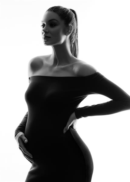 زن باردار جذاب با لباس مشکی ژست جدا شده در پس زمینه سفید