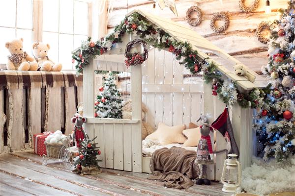 اتاق تزئین شده زیبا با درخت کریسمس با هدایایی در زیر آن - تصویر فضای داخلی خانه کریسمس در رنگ های آبی قرمز