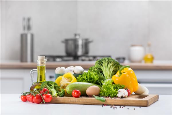 مجموعه ای از سبزیجات خام تازه گوجه فرنگی تخم مرغ قارچ سالاد فلفل کدو حلوایی روی یک میز چوبی سفید در یک اتاق آشپزخانه مدرن تغذیه سالم غذای ارگانیک