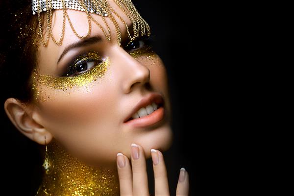 پرتره زن زیبا با زرق و برق طلایی روی صورتش دختری با آرایش هنری با درخشش های طلایی مدل مد با آرایش طلایی