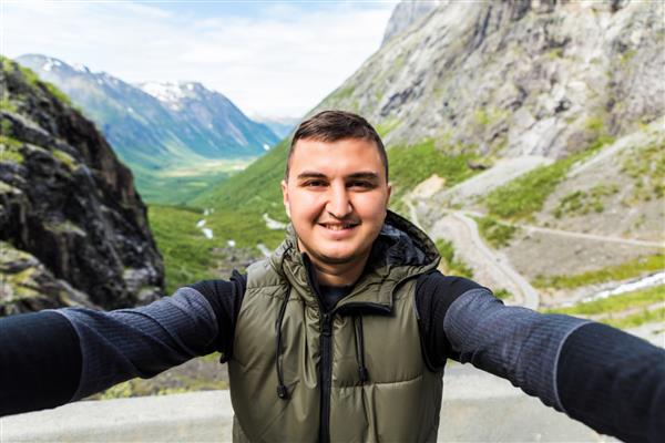 مرد ماجراجوی خوش تیپ در حال گرفتن سلفی در کوه مرد جوان قفقازی در حال لبخند زدن به دوربین