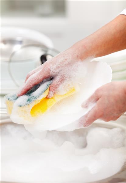 زنی در حال شستن ظروف در قسمت سینک آشپزخانه - نمای نزدیک روی دست