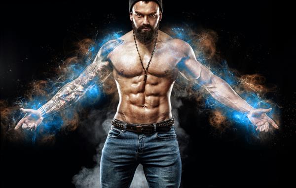 بدنساز ورزشکار در چراغ های انرژی آبی مرد خوش اندام با شلوار جین با خالکوبی در حال ژست گرفتن مفهوم ورزش و مد جدا شده در پس زمینه سیاه