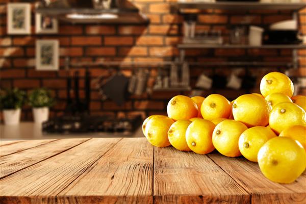 لیموهای زرد تازه روی میز چوبی در فضای داخلی آشپزخانه