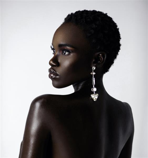 پرتره یک زن جوان سکسی سیاهپوست با موهای کوتاه مشکی و چوب لب مرطوب که یک گوشواره الماس بزرگ در مقابل پس‌زمینه‌ای روشن پوشیده است