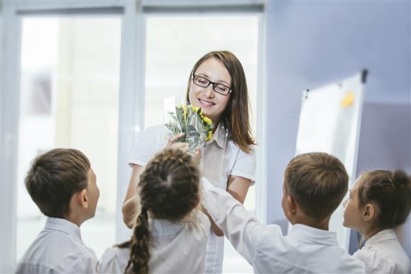 کودکان زیبا کودکان مدرسه با گل برای معلمان در مدرسه در تعطیلات