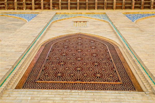 پنجره گره‌چینی مشبک و کاشی‌کاری‌های آبی بالای نمای آجری چهلستون