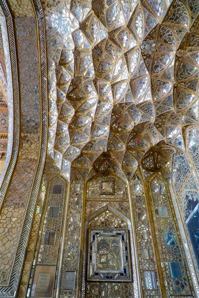 عکس نمای عمودی تالار آینه با سقف و دیوار مقرنس‌کاری شده آینه‌کاری شده و قاب عکس