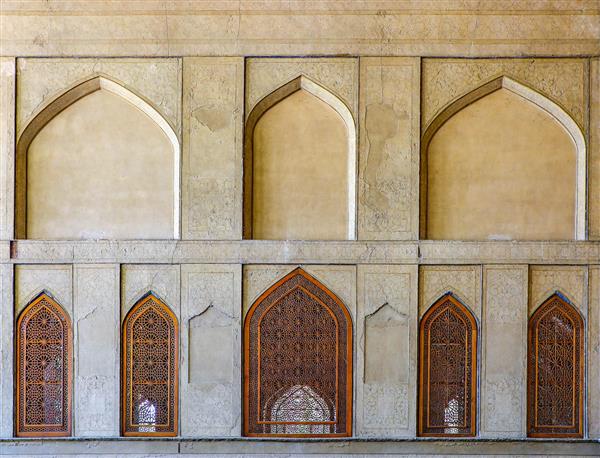 عکس نمای تقارن طاق‌های گچی و پنجره‌های چوبی مشبک در نمای داخلی یا خارجی عمارت صفوی