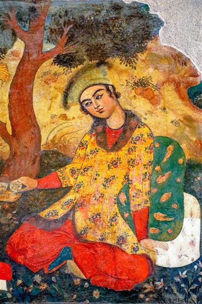 تصویر مرد جوان صفوی با لباس زرد گلدار و کلاه سبز در حال نشسته در باغ چهلستون