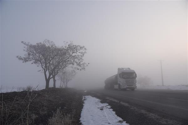 کامیون تانکر در حال حرکت در جاده مه‌آلود پوشیده از برف زمستانی