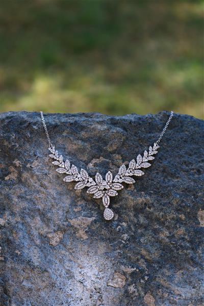 گردنبند زنانه شیک و مجلسی مدل برگ نگین‌دار روی سنگ برای تبلیغ جواهرات عروسی