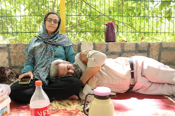 زوج مسافر در حال استراحت و تکیه دادن در طبیعت با فلاسک چای در سفر و کمپینگ