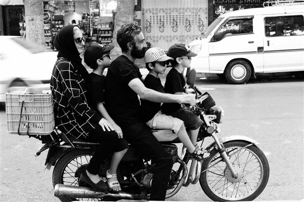 پرتره سیاه و سفید خانواده شلوغ پنج نفره در حال موتورسواری در خیابان شلوغ شهر