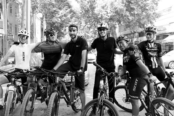 عکس سیاه و سفید تیمی دوچرخه‌سواران مرد با دوچرخه‌های کوهستان در خیابان شهری