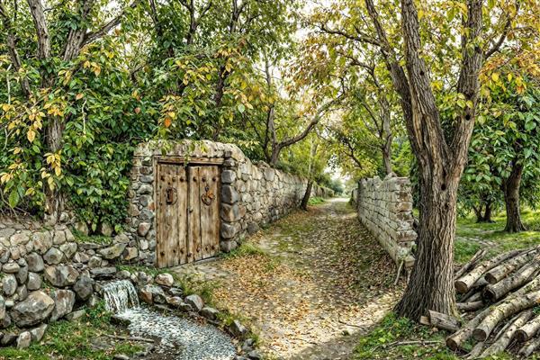 منظره پاییزی کوچه باغ با دیوار سنگی و در چوبی قدیمی مناسب دکوراسیون کلاسیک و سنتی پذیرایی جهت چاپ کاغذ دیواری و تابلو دکوراتیو