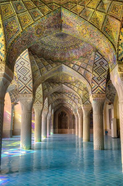 نمای داخلی مسجد با ستون‌های سنگی و نورهای رنگی مناسب پوستر دیواری سالن‌های بزرگ، لابی و فضاهای معنوی