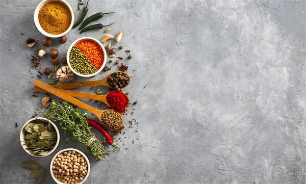 پس زمینه خاکستری با چیدمان قاشق های چوبی حاوی ادویه های رنگارنگ مناسب پوستر دیواری مدرن آشپزخانه و منوی رستوران