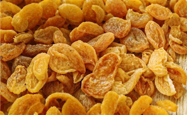 نمای نزدیک و بافت‌دار از برگه هلو و میوه‌های خشک شده زرد رنگ برای بسته‌بندی خشکبار، پوستر دیواری فروشگاه مواد غذایی و قنادی