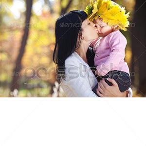 مادر جوان زیبا در جنگل پاییزی در حال بوسیدن دخترش