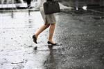 پاهای زن با کفش های پاشنه دار هنگام باران روی آب راه می روند