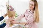 تحویل کارگاه گل مشتری سفارش خود را دریافت می کند - یک دسته گل لاله صورتی گل فروش دستی گل به خریدار می دهد