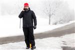 مرد با تلفن همراه در خیابان یخ زده راه می رود