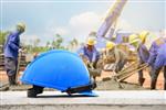 کلاه ایمنی در محل ساخت و ساز و پس زمینه کارگران ساختمانی