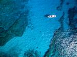نمای هوایی از تعطیلات ساحل جزیره گرمسیری در صخره های آبی اقیانوس قایق بادبانی