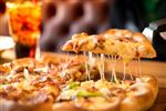 تکه ای از غذاهای دریایی پوسته پنیر پیتزا با سبزیجات فلفل زنگ خوراکی فست فود خوشمزه و خوشمزه ایتالیایی سنتی و نوشابه گازدار با مردان نشسته بر روی میز مبل چوبی روی میز روی میز