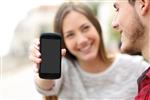 زن و شوهر خوشبختی که در فضای باز در صفحه خالی تلفن هوشمند برنامه هایی را نشان می دهند