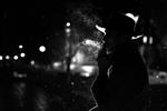 شبح تاریک مردی با کلاه در حال کشیدن سیگار زیر باران در خیابان شبانه به سبک نوآر