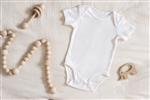 عکس استوک طرح‌دار از Onesie نوزاد سفید شفاف با اسباب‌بازی‌های چوبی کودک نوپا روی دستمال عاج برای ایجاد ماکت برای ارائه طرح تصعید کودکان