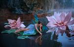 یک زن زیبا یک پری ناز با بال های پروانه روی برگ سبز نیلوفر آبی خوابیده است مناظر فانتزی از گل های صورتی بزرگ در دریاچه پوره رودخانه دختر پیکسی با لباس آبی دختری که آب را لمس می کند