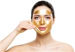 ماسک صورت لایه برداری طلایی زن مدل زیبایی که ماسک طلایی پوست را از پس زمینه سفید پاک می کند مراقبت از پوست صورت و لوازم آرایشی